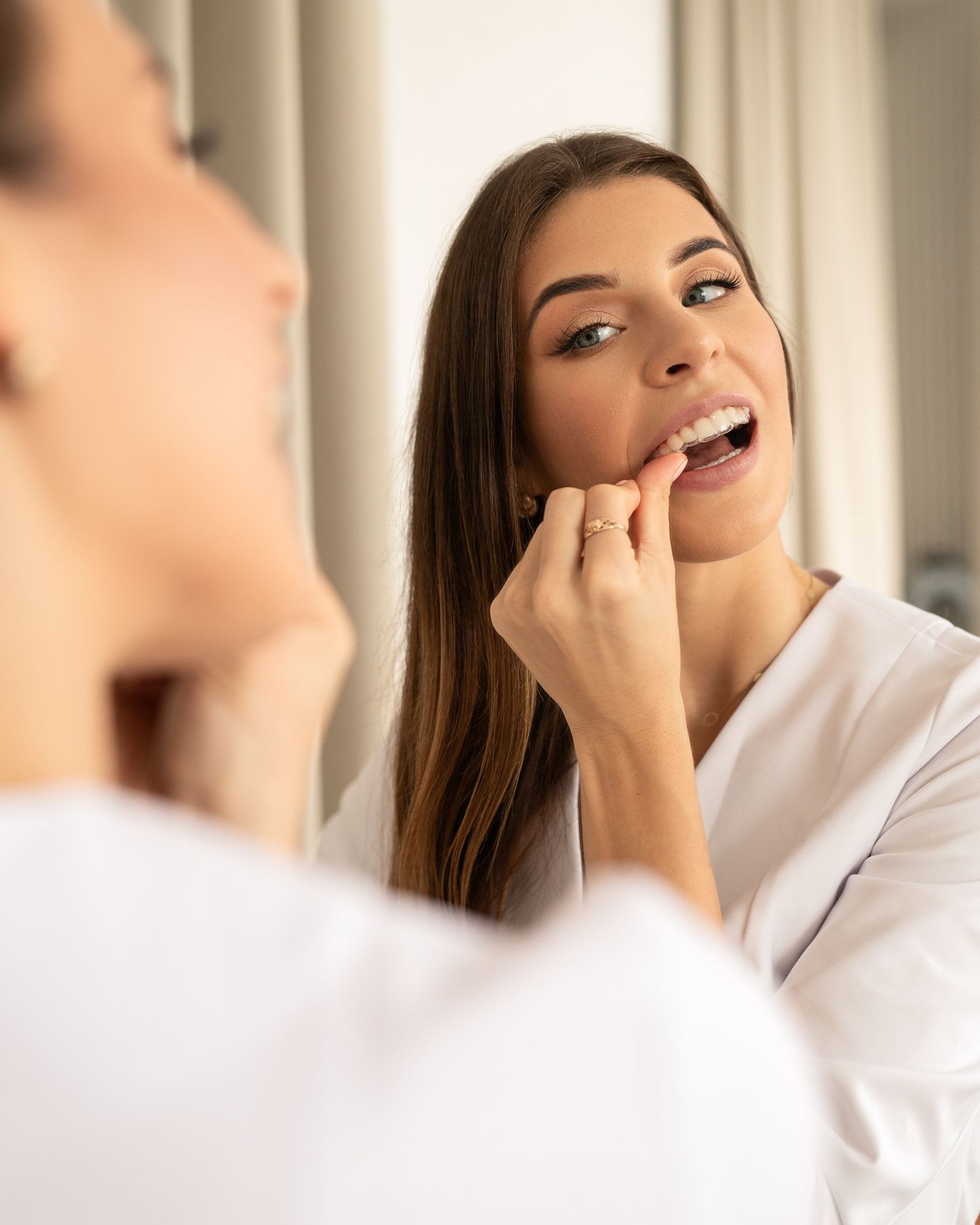 Explore the expertise of a leading female international orthodontist in Poland, adorned in a professional white suit within an elegant clinic setting. Renowned for her beauty, sharp professionalism, and fluency in six languages, she specializes in state-of-the-art clear aligner orthodontic treatment. This exclusive practice, with locations in Lodz and Warsaw, boasts modernity, as showcased by the orthodontist holding clear aligners and a sleek Mac computer. Elevate your orthodontic experience with this top-tier practitioner, delivering unparalleled care in the heart of Poland